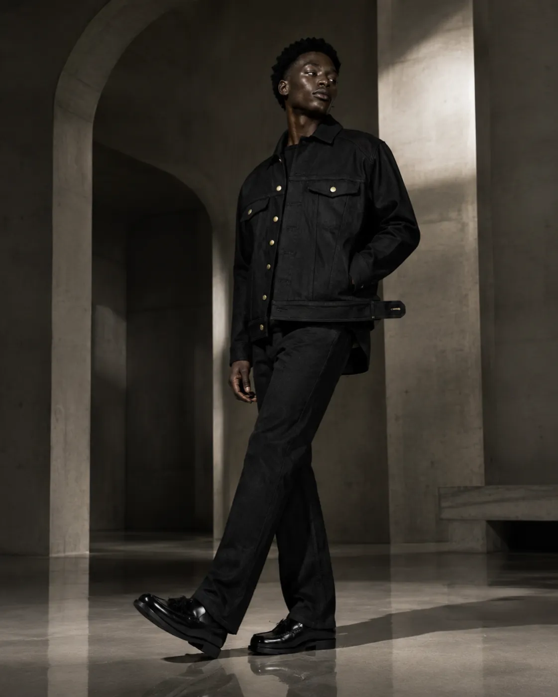 The Uniform in black — full length under concrete arches.