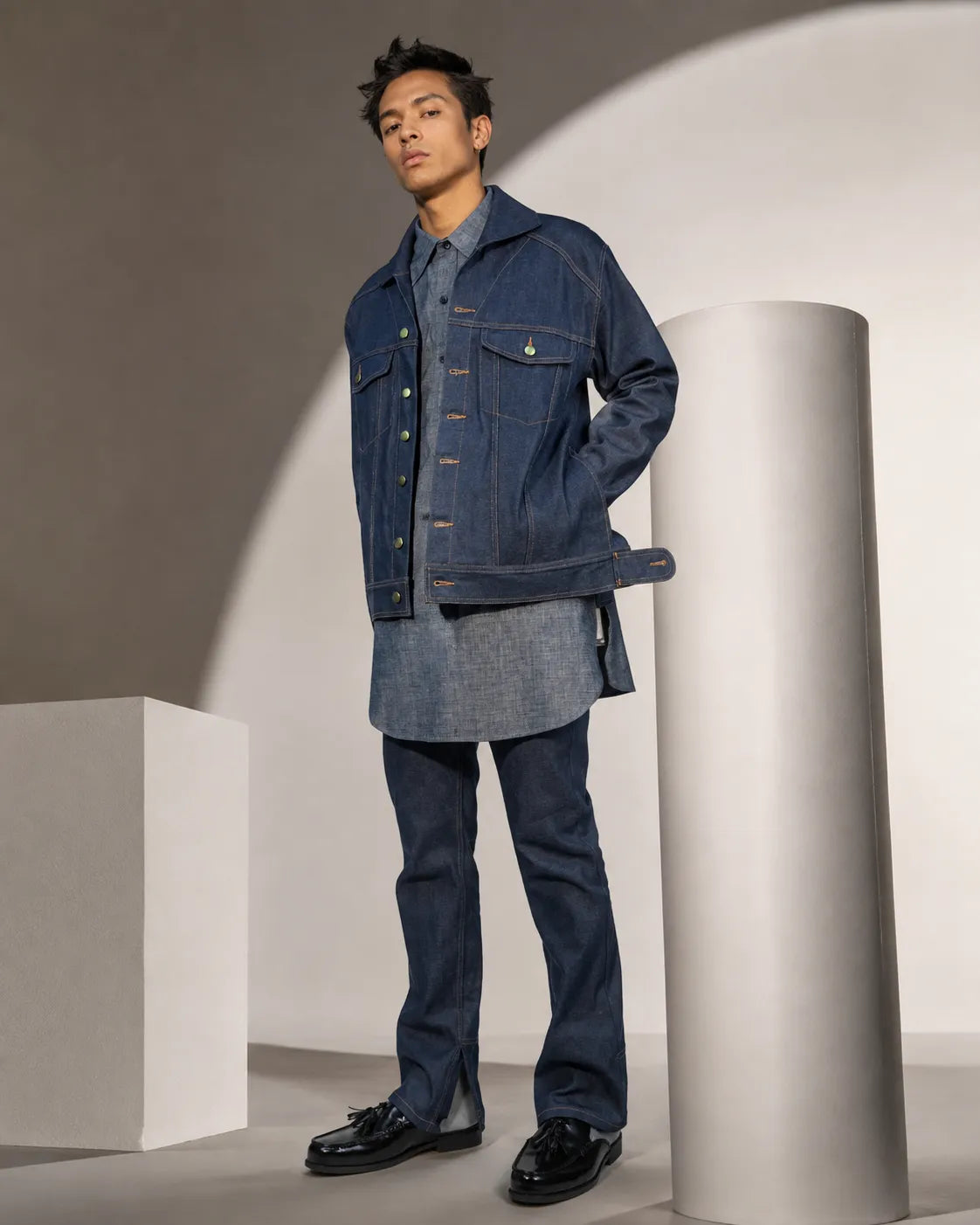 The Uniform in blue — jacket over the button down with the jeans, standing.